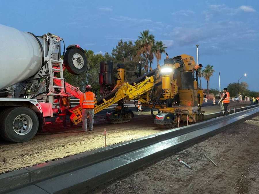 Curb machine fed by a mixer at dusk