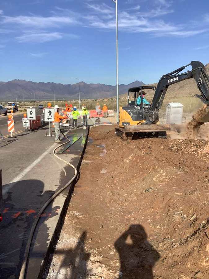 Excavating and grading with a water hose on dust control