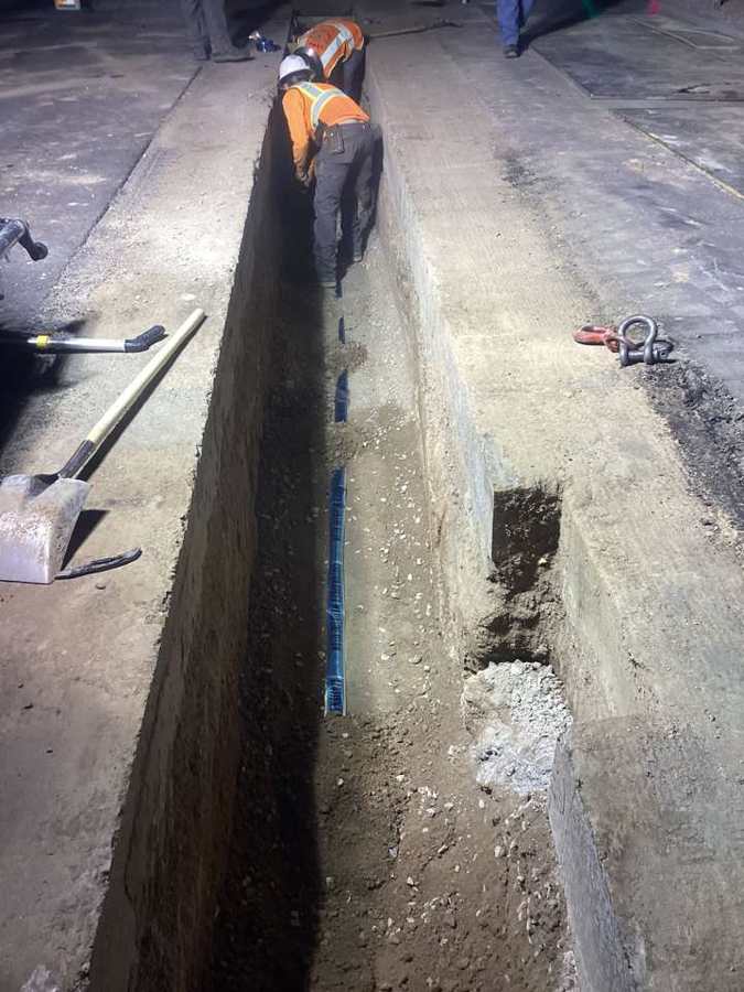 Night crew laying a water line with warning tape