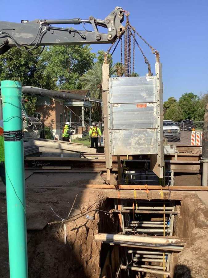 Lowering trench shoring for a deep sewer main